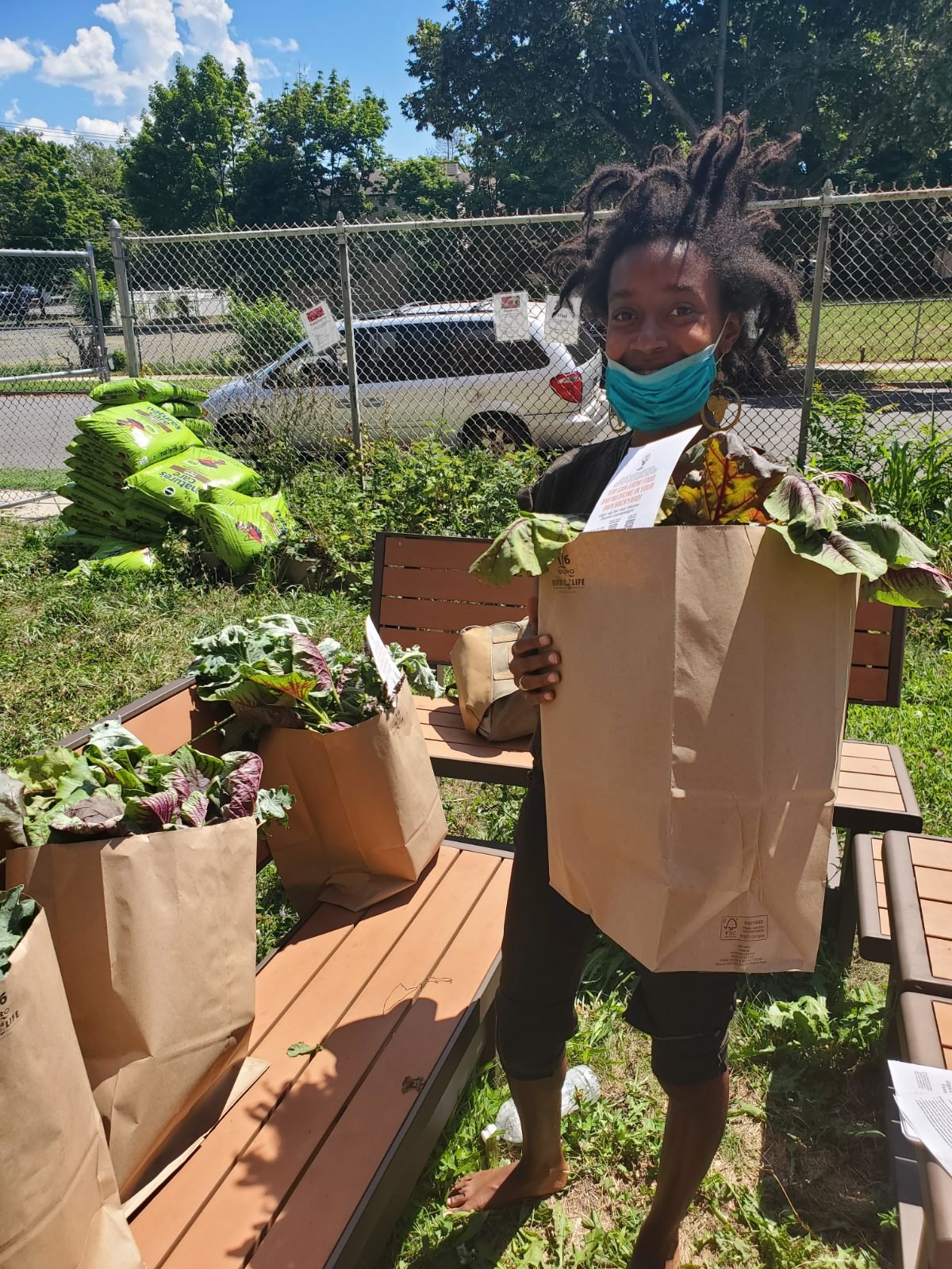 Root Life photograph: a neighbor holding up a full kraft sack of just-cut greens on pickup day